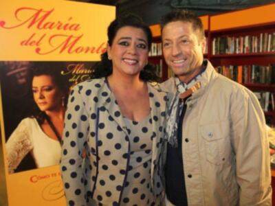 Una pareja sonriente frente a una portada de libro con el nombre 'María del Monte'.