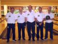 Equipo de bowling en una sala de juegos, con insignias nacionales y un bowling negro.