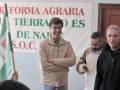 Un grupo de personas frente a un cartel que dice "Reforma Agraria: La Tierra es de Nuestra S.O.C.".