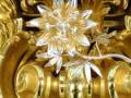 Detalle de un ornamento dorado con una flor plateada en relieve, mostrando la perfección y detallismo de la artesanía.