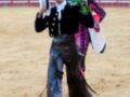 Un torero en el ring, con un traje tradicional y un sombrero, posando con una flor en la mano.