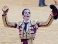 Joven torero celebrando con gesto victorioso en la plaza de toros.