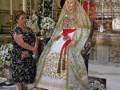 Dos mujeres, una con vestido floral y otra con traje tradicional, posan frente a un altar en una iglesia. La imagen muestra detalles de vestimenta y decoración religiosa típica.