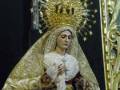 Imagen de una Virgen con vestimenta dorada y un manto blanco, rodeada por detalles artísticos en oro.