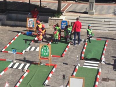 Niños participando en una actividad educativa de tráfico en un área simulada de carretera.