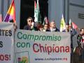 Manifestantes con pancartas y banderas, incluyendo una que dice "Compromiso con Chipiona" y un banner informativo.