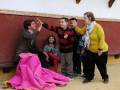 Una escena de una familia feliz en una plaza de toros, con un niño levantando una muleta rosa en el aire.