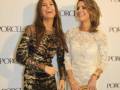 Dos mujeres sonrientes posan frente a un fondo con el logo de Porcelanosa. La imagen parece ser de una celebración o evento corporativo.