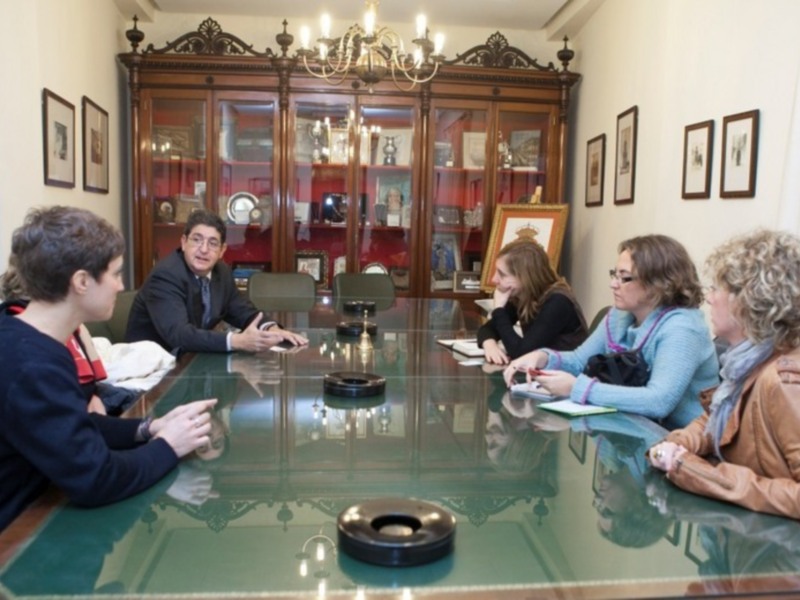 Una reunión en una sala de conferencias con una mesa redonda y una vitrina con objetos antiguos en el fondo.
