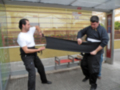 Dos personas trabajando juntas para estirar una manta en una parada de autobús.