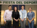 Celebración del deporte con cuatro personas posando en un evento oficial bajo el letrero 'Fiesta del Deporte'.
