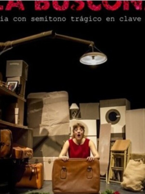 Una escena teatral con una mujer en un entorno de cartón y objetos cotidianos, con un título en rojo que sugiere una combinación de humor y trágico.
