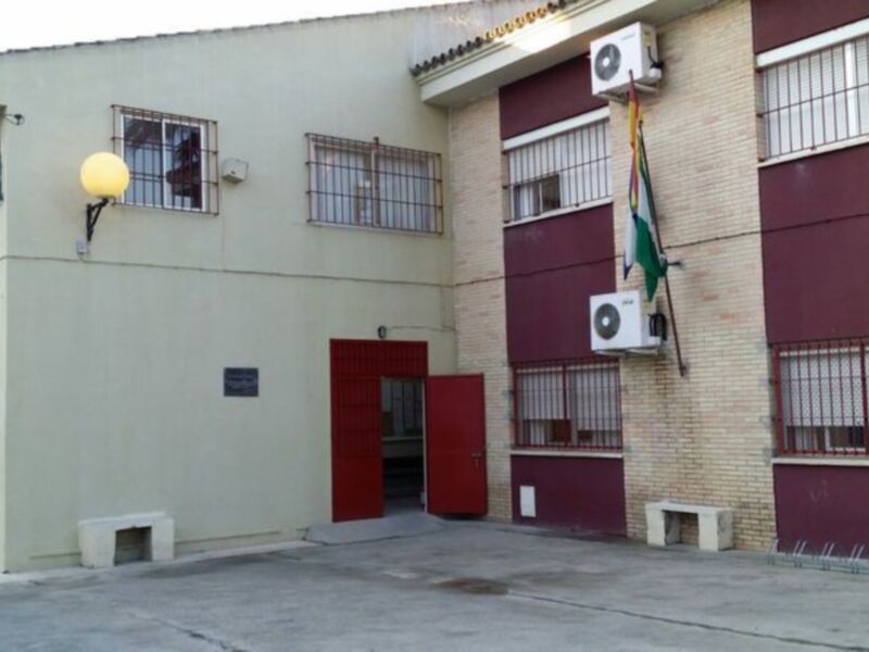 Edificio con ventanas y puerta roja. Bandera en la fachada. Suelo de hormigón.