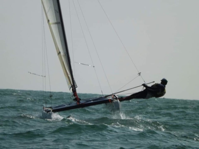 Barco de vela navegando en el mar con un viento fuerte, mostrando la habilidad del marinero para controlar la velas.