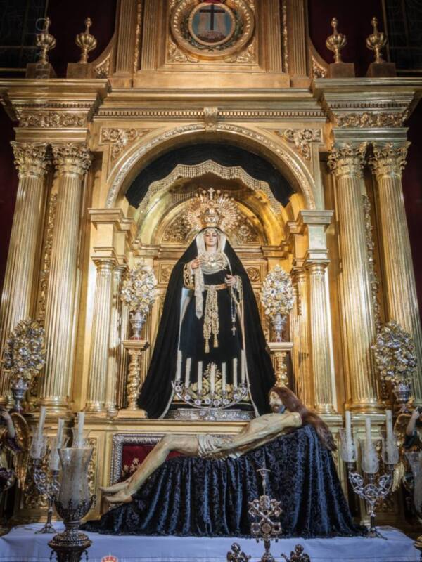 Altar con la imagen de la Virgen de la Soledad en el centro, rodeada de ornamentación dorada y un Cristo en la base.