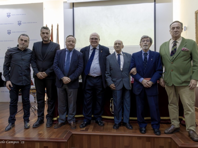 Grupo de personas en trajes formales posando frente a una pantalla con un logo.
