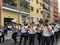 Músicos tocando instrumentos en una calle, frente a edificios de colores.